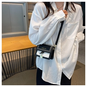 Dettaglio mini borsa a tracolla bicolore bianco e nero con borchie dorate e nodo intrecciato