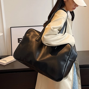 Minimalist black faux leather large capacity tote bag worn by a model in a trench coat
