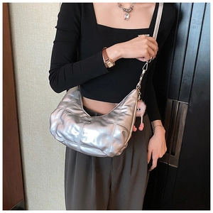 Detail van zilveren metallic tas met geometrisch stiksel en roze pluchen bedeltje