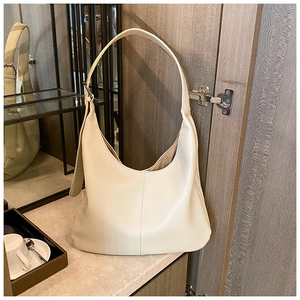 Detailed macro view of the cream leather texture and wide strap on the hobo shoulder bag