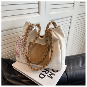 Detail of heart-embossed cream leather tote bag with braided handle and silk scarf