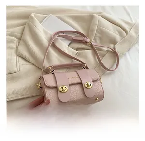 Détail d'un sac à main rose effet croco avec double fermoir rotatif et poignée supérieure