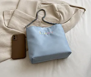 Macro shot of blue oxford bucket bag showing lucky embroidery and daily capacity