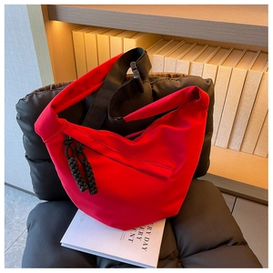 Gros plan d'un sac demi-lune en nylon rouge avec sangle réglable et tirette tissée