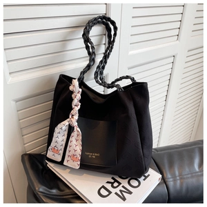 Detail of black tote bag with heart embossed pattern, woven strap and silk scarf
