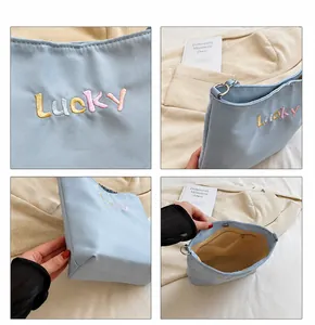 Detail view of light blue Oxford bucket bag showing Lucky embroidery and inner zip pocket
