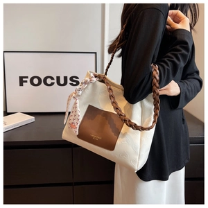 Close-up of cream canvas tote featuring heart embossed texture and woven leather strap