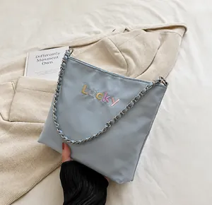 Detail of light blue bucket bag featuring Lucky embroidery and silver chain strap