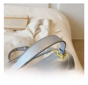 Dettaglio del manico della borsa in pelle grigio argento con fibbie in metallo oro