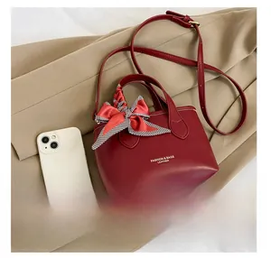 Red leather bucket bag with fashion print and plaid scarf detail next to a smartphone