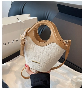Détail du sac seau bicolore avec poignée anneau et texture en cuir à motif gaufré