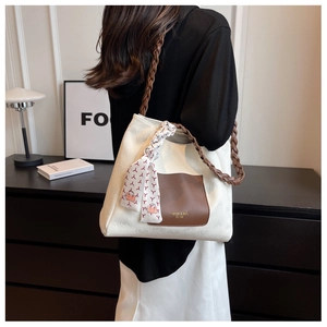 Detail view of heart-embossed white canvas tote with woven brown handle and silk scarf