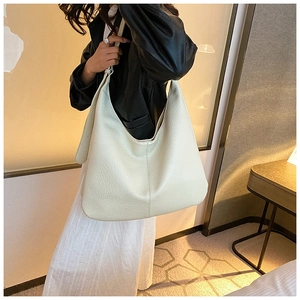 Detail of a large off-white bucket bag showing the soft lychee leather texture