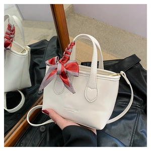 Macro detail of white mini bucket bag featuring fashion text and houndstooth ribbon