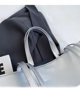 Détail des anses du sac fourre-tout argenté avec coutures précises sur similicuir de qualité