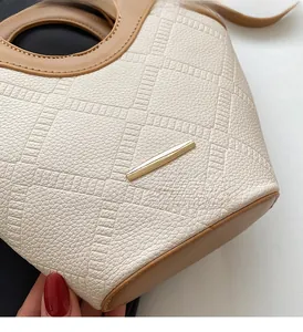Détail de la texture cuir et des finitions métalliques dorées sur un sac seau