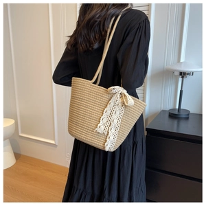 Detail of hand-woven straw tote bag with elegant white lace ribbon decoration