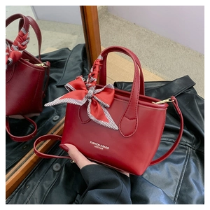 Detail of red mini bucket bag with fashion print and checkered bow on handle