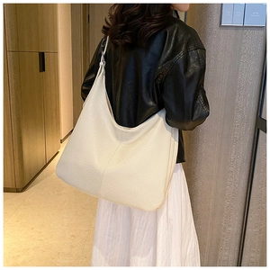 Chic cream white hobo bag in lychee pattern leather shown on shoulder of a model