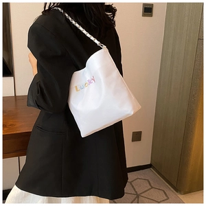 Detail der weißen Beuteltasche mit buntem Lucky-Print und silbernem Kettenriemen