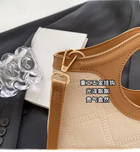 Gros plan détaillé d'un sac en cuir crème avec garniture brune et ferrures dorées