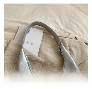 Détail du sac hobo argenté sur un blazer beige soulignant la finition en cuir texturé