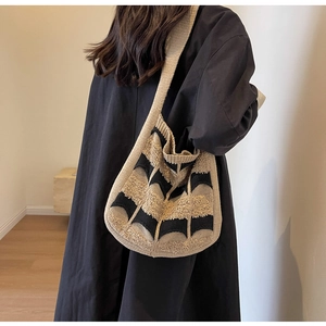 Sac hobo tricoté à rayures beiges et noires porté par un mannequin pour un look décontracté