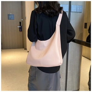 Detailed back view of a minimalist nude pink pebbled leather hobo bag on a shoulder