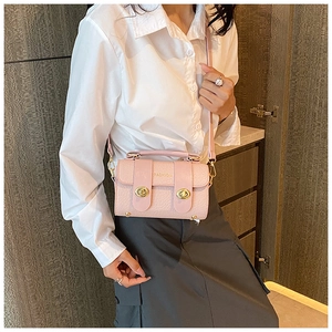 Détail du sac à bandoulière rose clair avec fermoirs dorés et cuir texturé