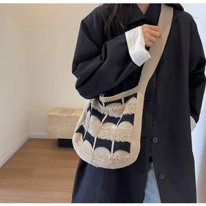 Détail d'un sac bandoulière en tricot beige et noir avec une finition bouclée texturée