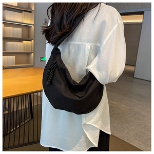 Détail du sac demi-lune en nylon noir avec breloque en corde tressée sur la sangle