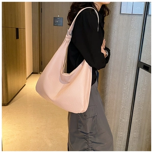 Minimalist light pink leather tote bag shown on model in a modern indoor setting