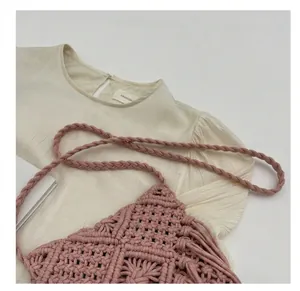 Detail of pink macrame woven bag with thick shoulder strap and bohemian fringe accents