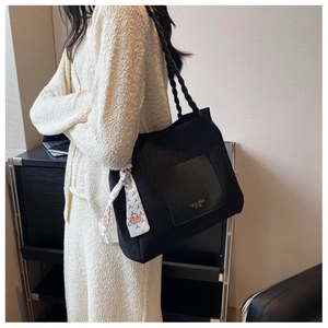 Detailed view of black canvas tote bag with woven handles and silk scarf decoration
