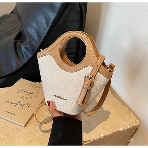 Détail du sac seau matelassé ivoire avec finitions en cuir marron et poignée ronde