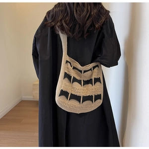 Détail d'un sac cabas en maille avec motif géométrique tissé noir et beige porté