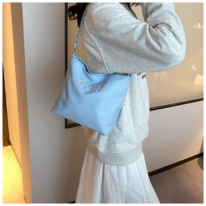 Detailaufnahme der hellblauen Nylontasche mit bunter Lucky-Stickerei und Kettenriemen