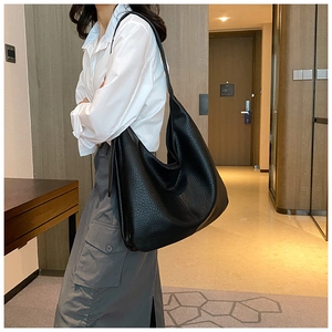 Detailed view of large black bucket bag with lychee texture leather on a female model