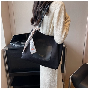 Detail of black canvas tote bag with heart embossing and decorative woven strap with scarf