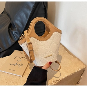 Détail d'un sac seau chic en cuir mesh crème et cuir lisse marron avec poignée ronde