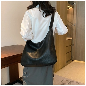 Detailed back view of a large black pebbled leather tote bag worn on a model's shoulder