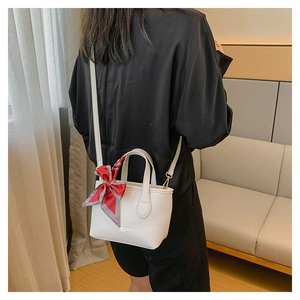 White bucket bag with silk scarf detail shown on shoulder in a cozy home setting