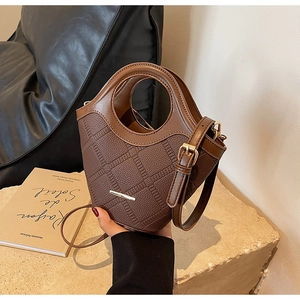 Détail du sac en cuir grainé avec une grande poignée circulaire et barre en métal doré