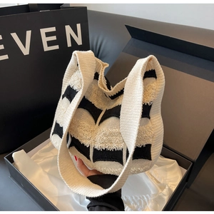 Détail d'un sac cabas tissé avec franges présenté dans un élégant coffret cadeau noir