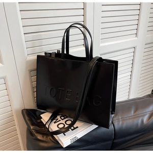 Gros plan du sac fourre-tout noir avec logo embossé et texture cuir élégante