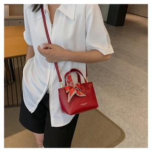 Fashionable red bucket bag with plaid silk scarf detail and adjustable crossbody strap
