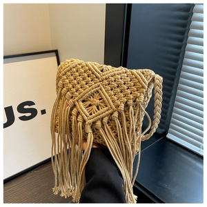 Detail of handmade beige macramé straw bag featuring geometric patterns and long fringes