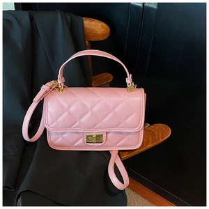 Dettaglio della borsa in pelle trapuntata rosa con chiusura dorata su sedia in legno