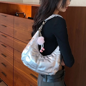 Zilveren gewatteerde hobo-tas met roze hanger gedragen door model in stijlvol interieur