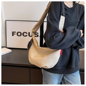 Détail du sac bandoulière beige en nylon demi-lune avec large sangle sur mannequin